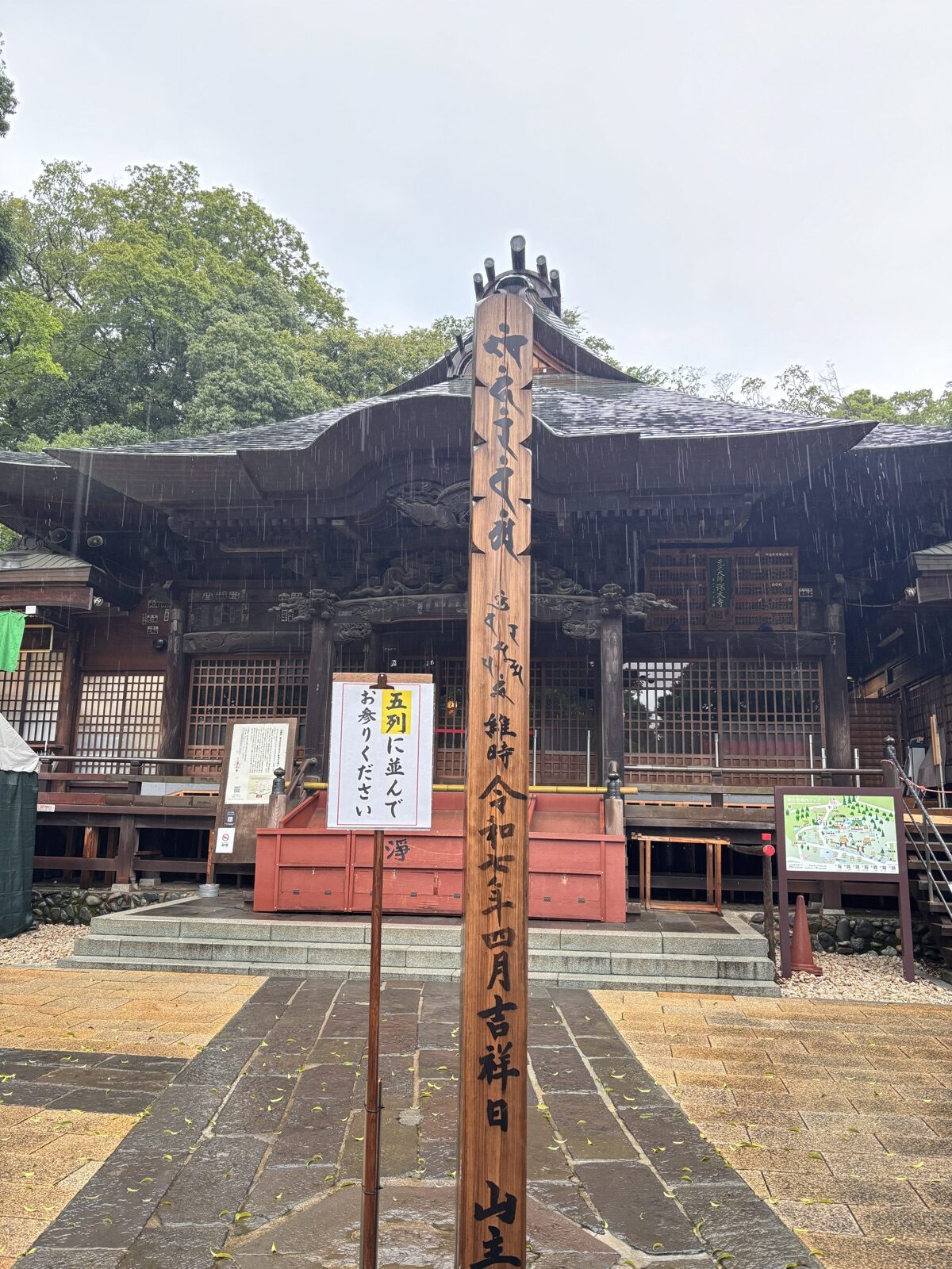 雨の降る元三大師堂と参拝案内の立て札